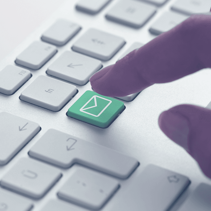 A finger pressing a green email envelope key on a keyboard, representing automated email sending.